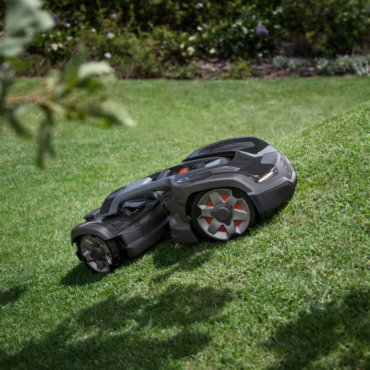 Ein schwarzer Rasenmäher-Roboter auf grünem Rasen mit roten und grauen Akzenten.