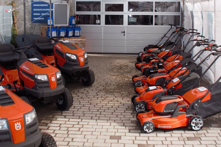 Rasenmäher und Aufsitzmäher in leuchtendem Orange und Schwarz in einem Showroom aufgestellt.